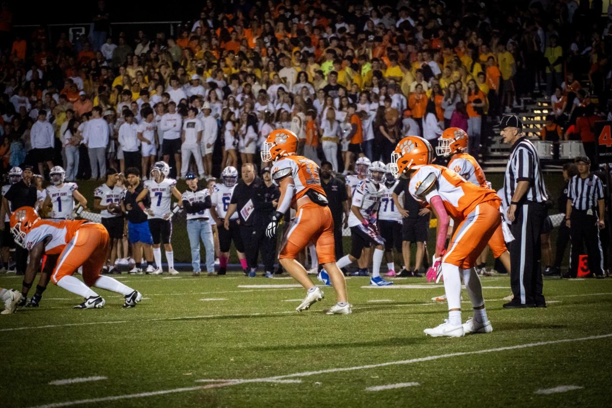 Kael Morosko (Middle) and the Cougars defense set up pre-snap as Fallston’s student section, dressed in class colors, watch their win over North East on homecoming. 