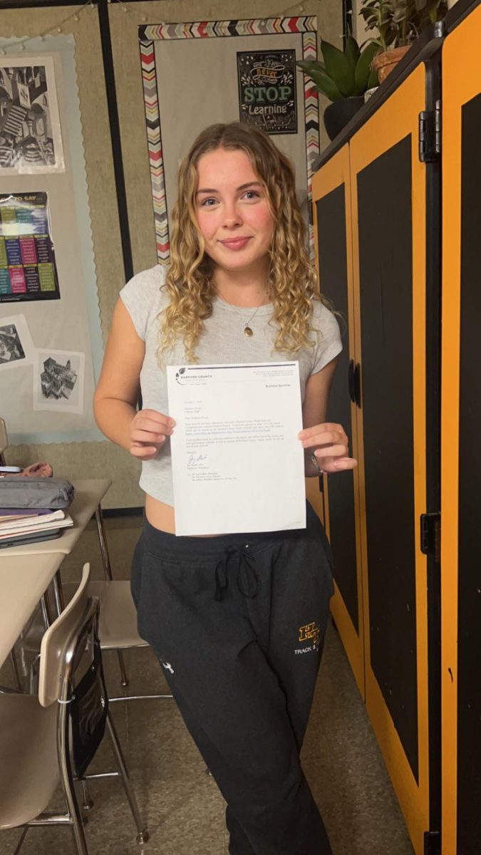 Madi proudly posing with her letter! (Photo Courtesy of Kaitlyn Hughes) 