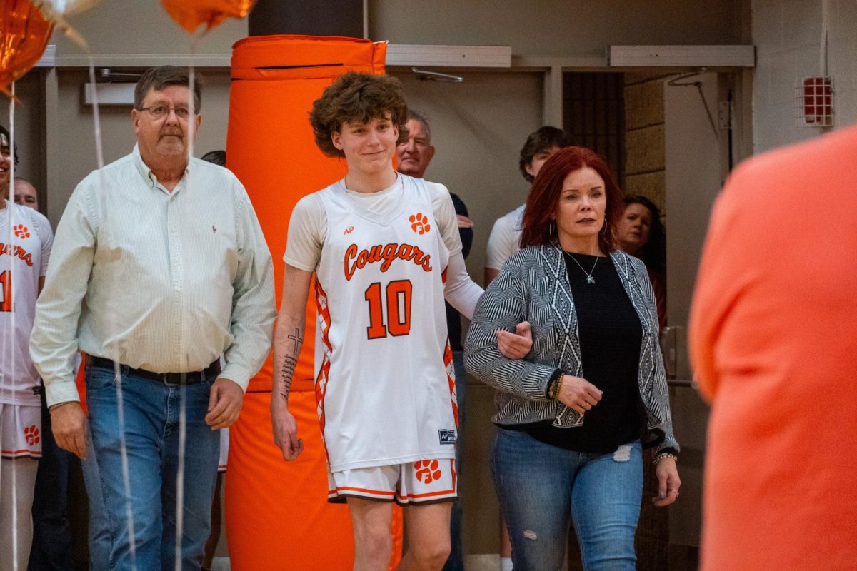 Senior Eli Pearce walks to his coaches, escorted by his parents, during senior night festivities prior to the game. Photo Courtesy of Joseph Mullen.